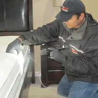 Bed bug inspection technician checking a mattress and bed frame for signs of infestation in Madison, WI