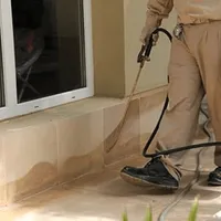 General pest control technician spraying exterior perimeter around a home in Madison, WI