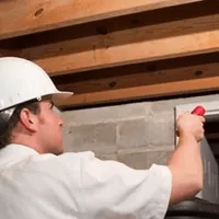 Termite inspection technician checking a basement wall and framing for termite activity in Madison, WI